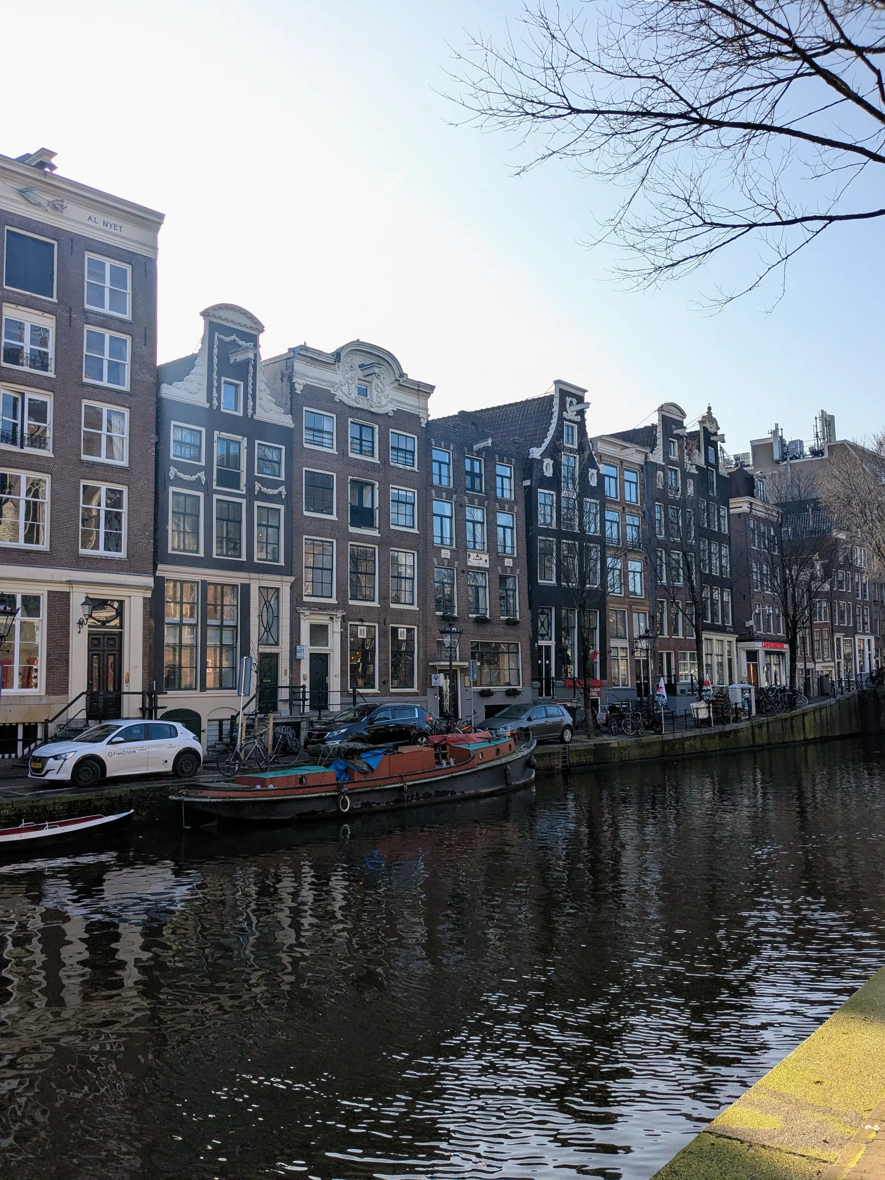 Narrow Amsterdam canal houses beside calm water