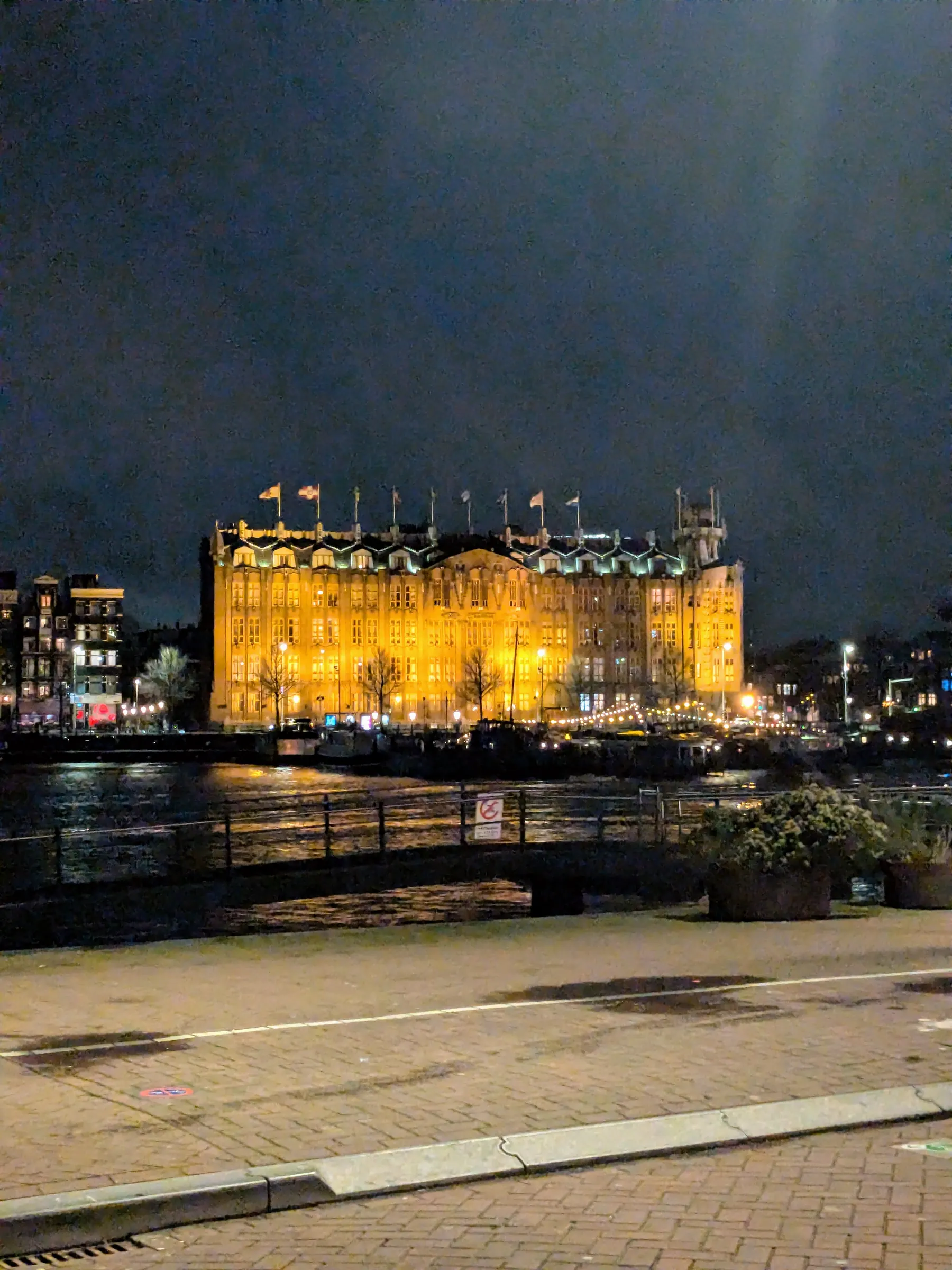 A lit building beside the water at night in Amsterdam
