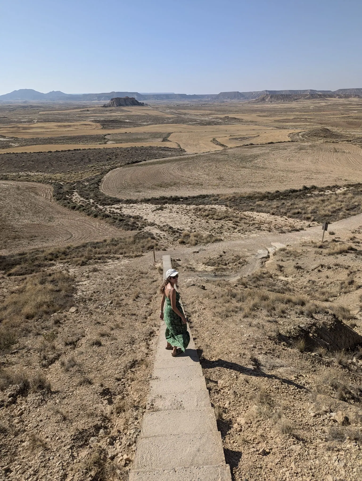 A traveler walking down steps towards the dry desert landscape of Bardenas Reales in Navarra