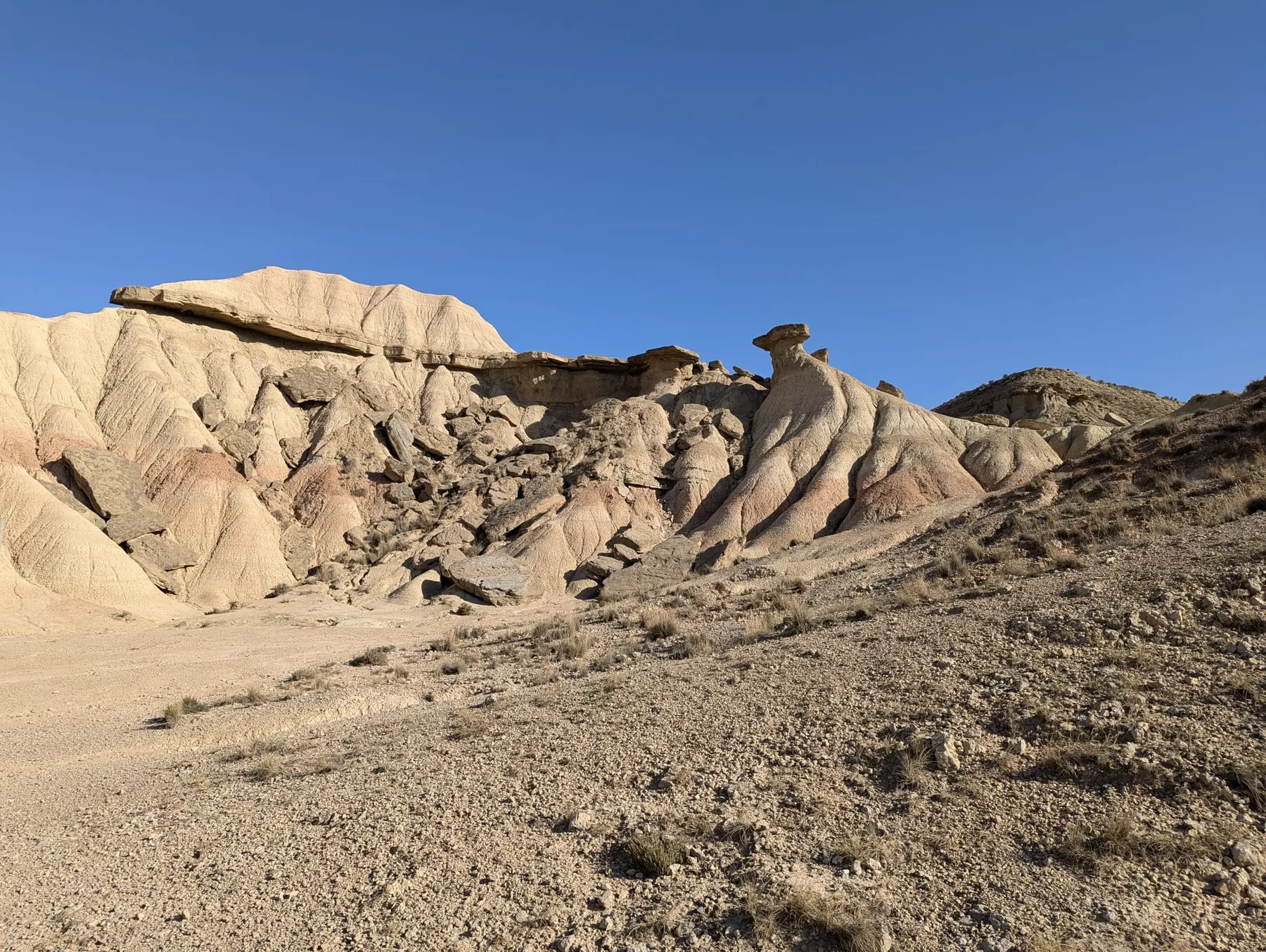 Eroded cream and orange rock formations in Bardenas Reales under a blue sky