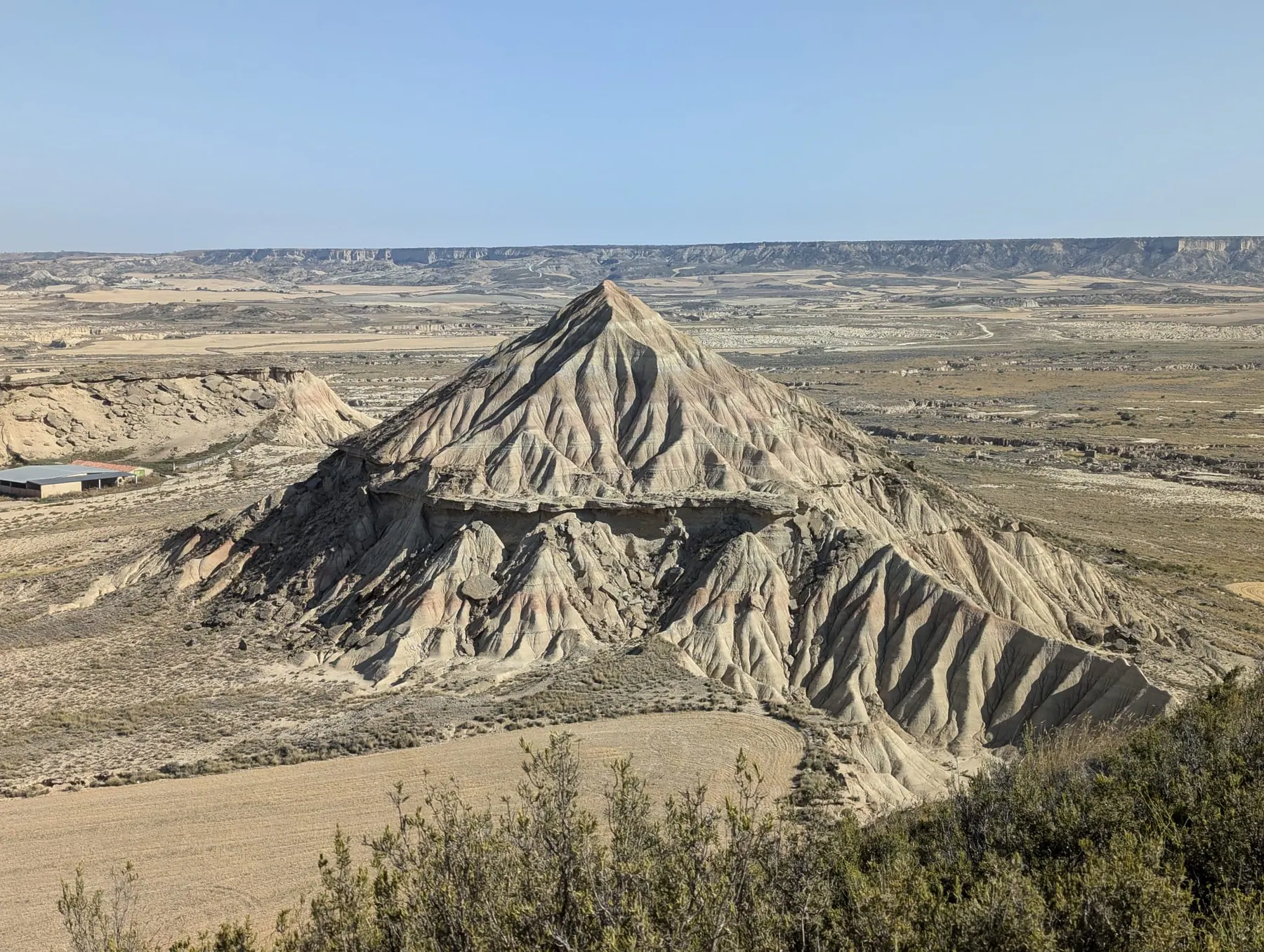 A large eroded hill rising above the dry plains of Bardenas Reales