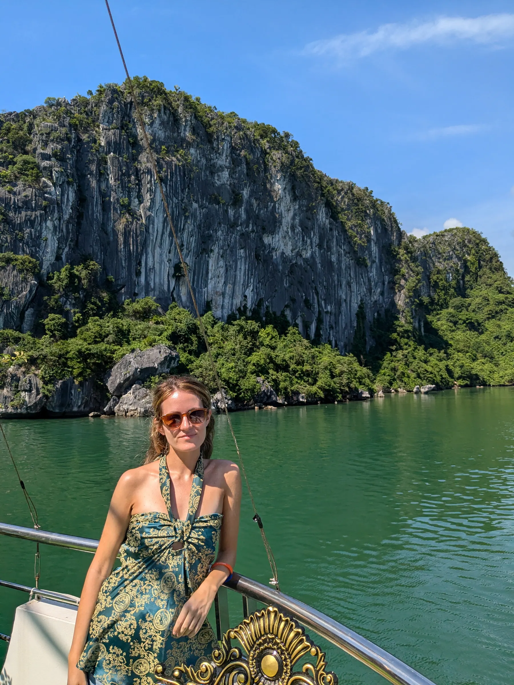Zane standing on a wooden boat deck facing towering limestone karst pinnacles in Lan Ha Bay