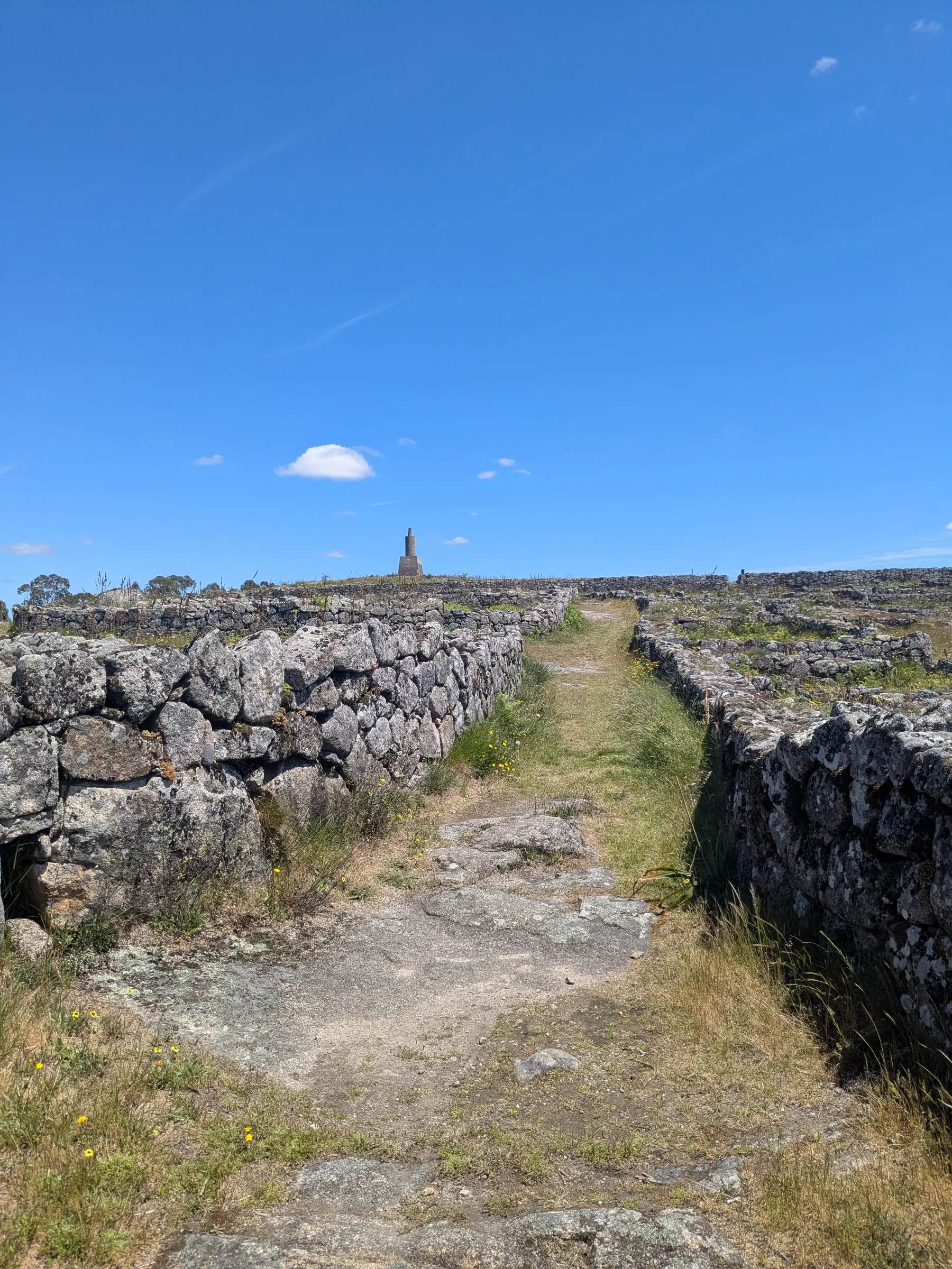 Stone paths and walls at Citânia de Sanfins under a blue sky