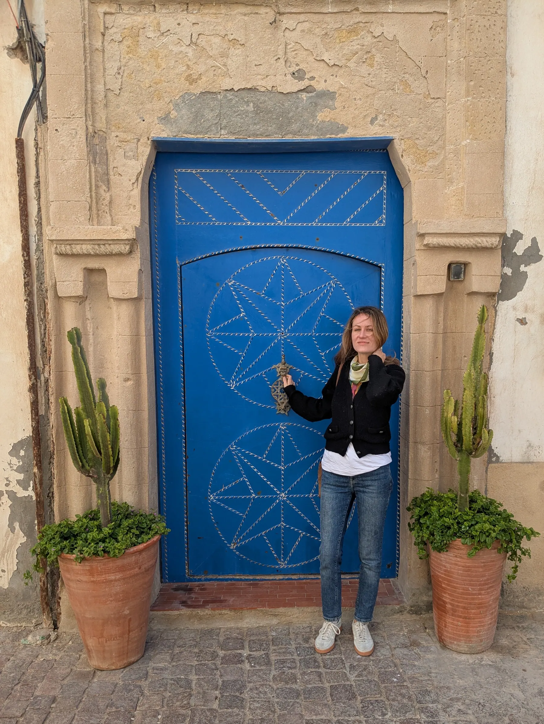 A traveler standing beside a blue Moroccan door in Essaouira