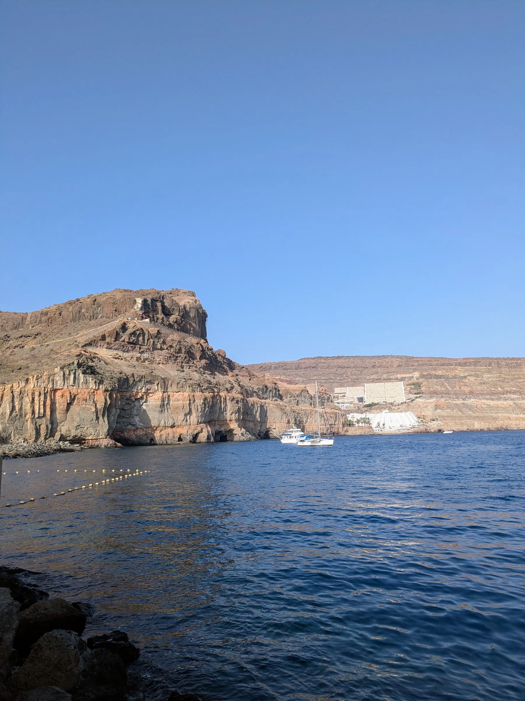 Rocky cliffs and calm blue water beside Puerto de Mogán