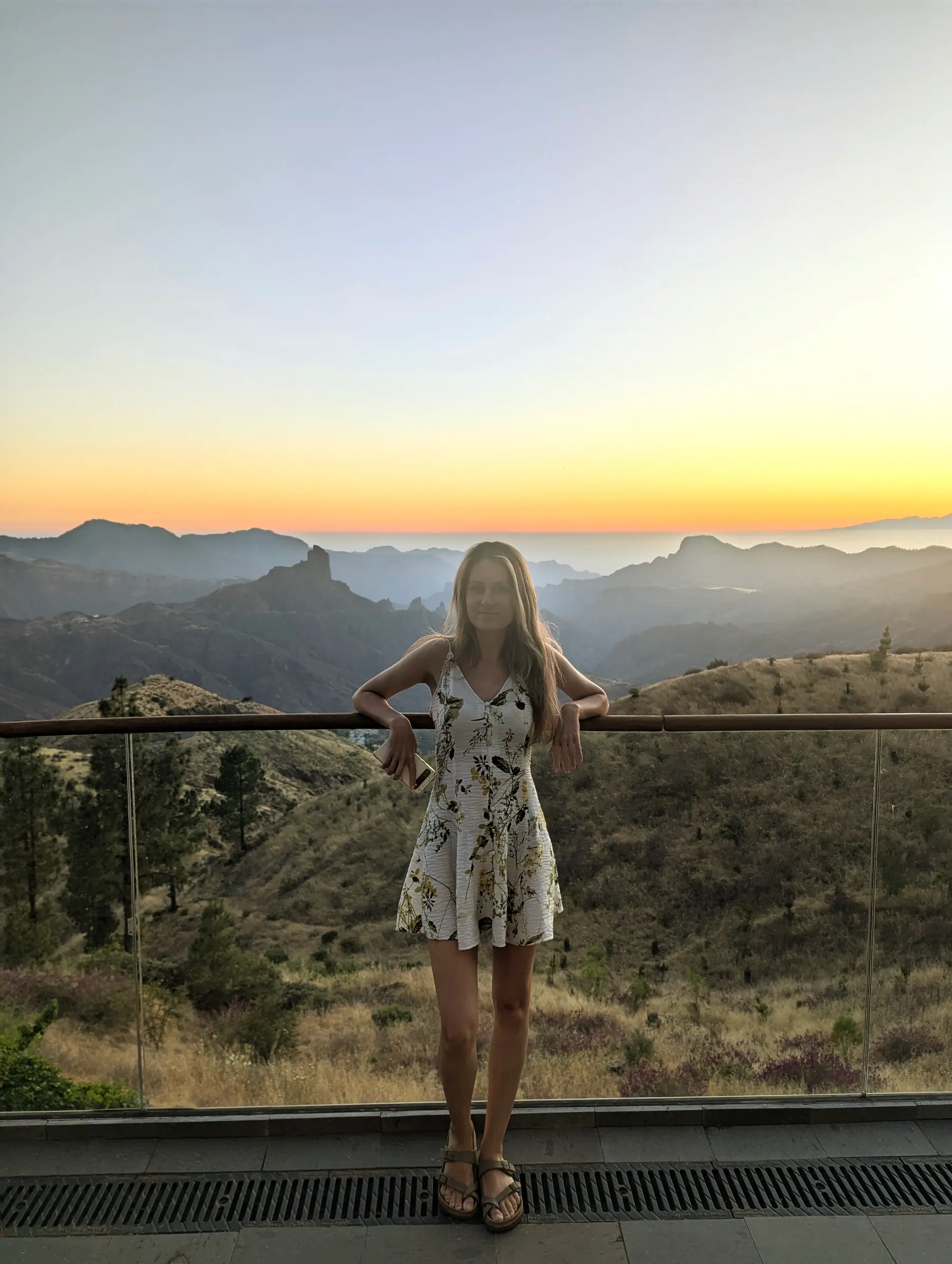 A traveller at a mountain viewpoint above Gran Canaria's layered volcanic ridges at sunset