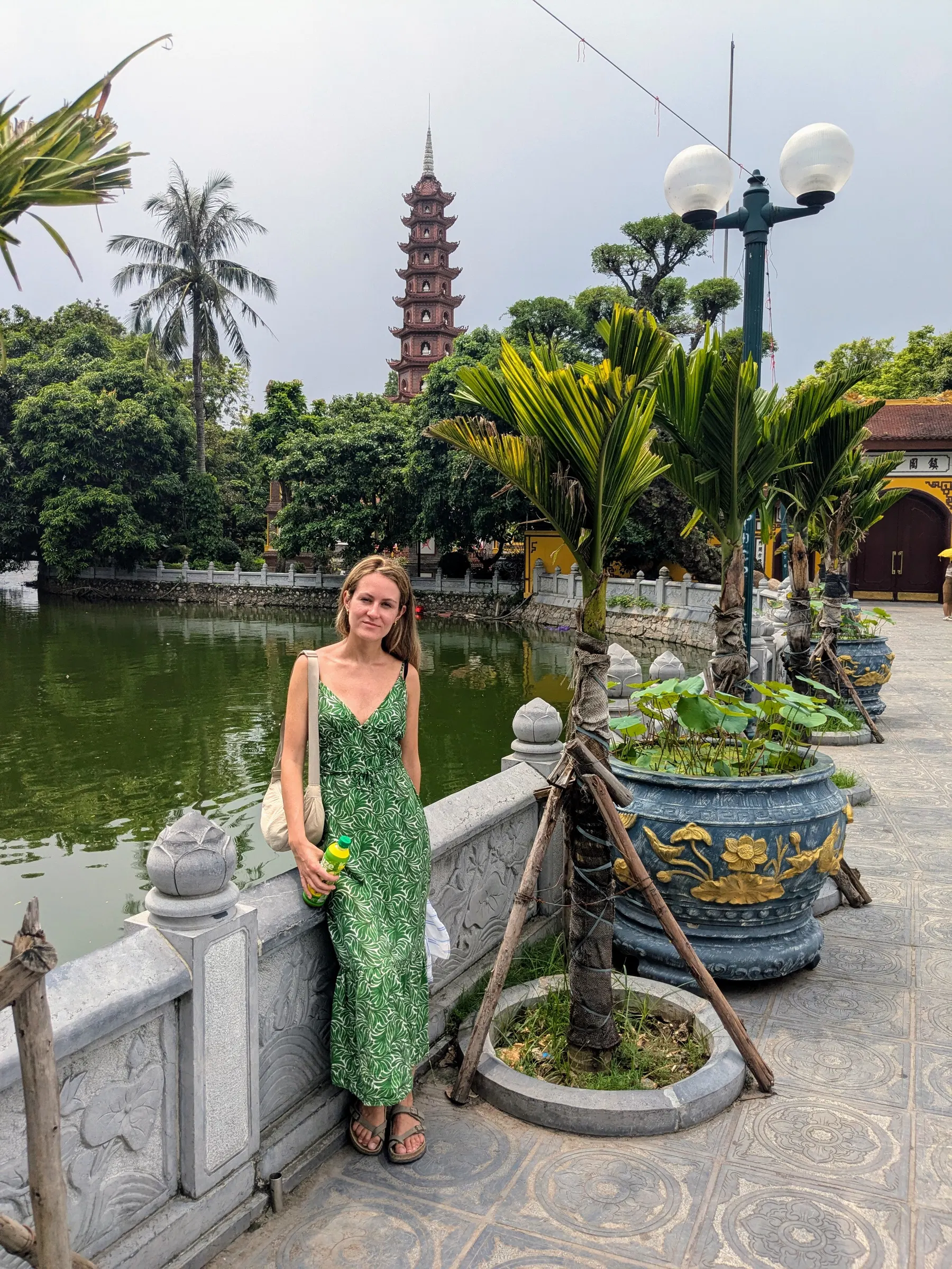 A traveller standing beside the red stupas of Tran Quoc Pagoda on West Lake in Hanoi
