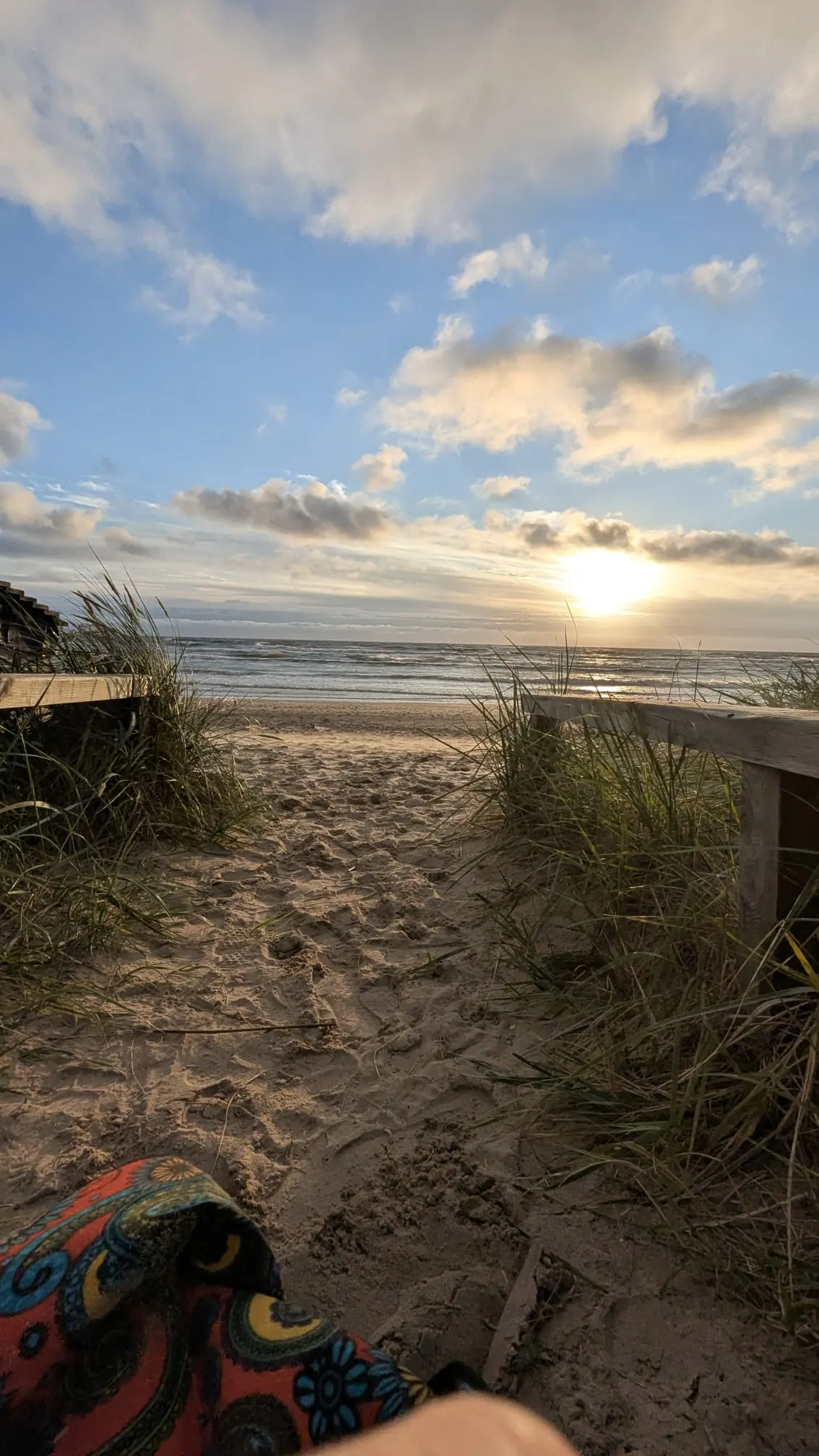 The sun setting over the Baltic Sea beyond the grassy dunes at Jūrkalne