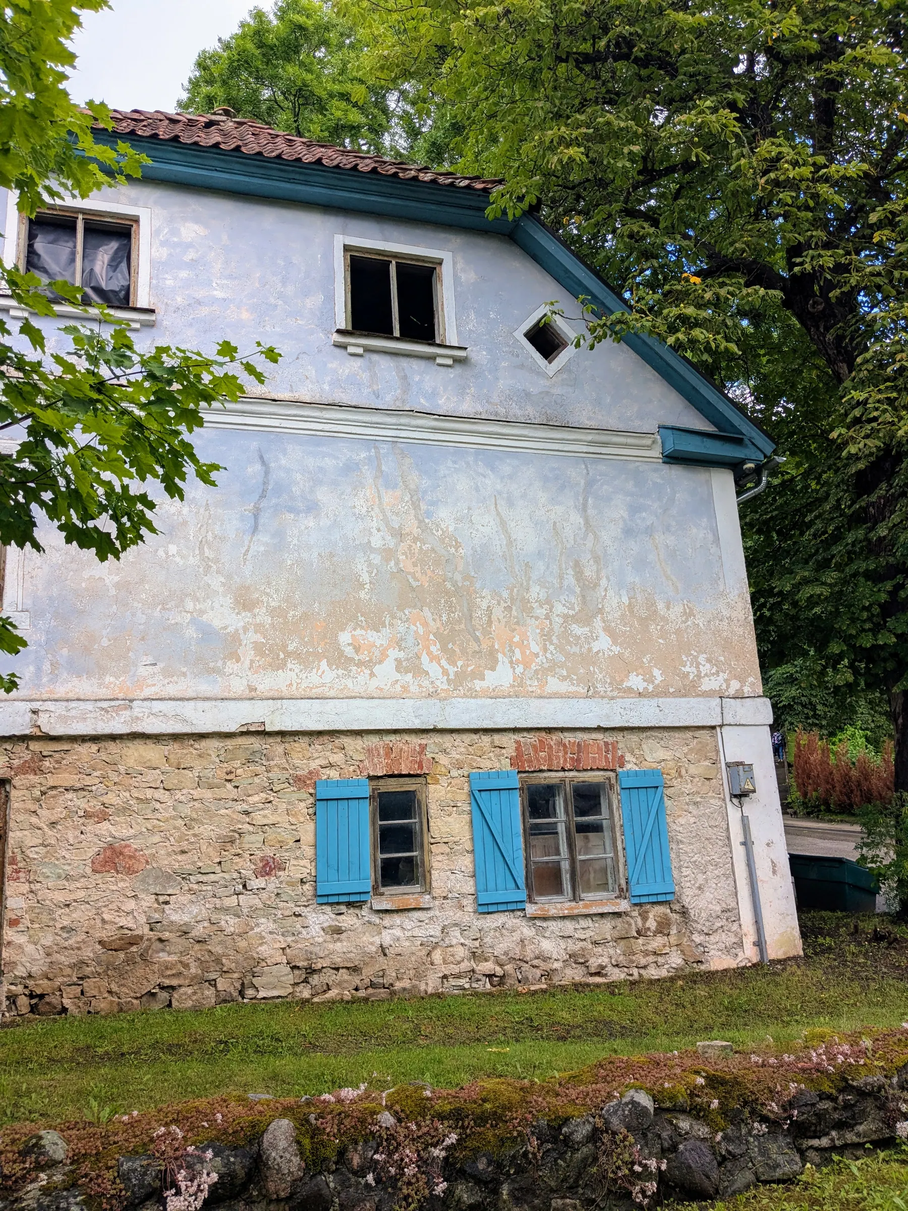 An old pale blue Sabile house with bright blue wooden shutters