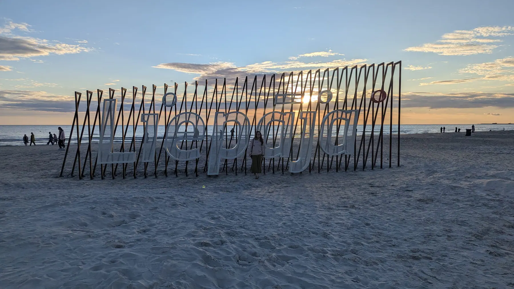 A wooden door installation silhouetted against sunset on Liepāja beach