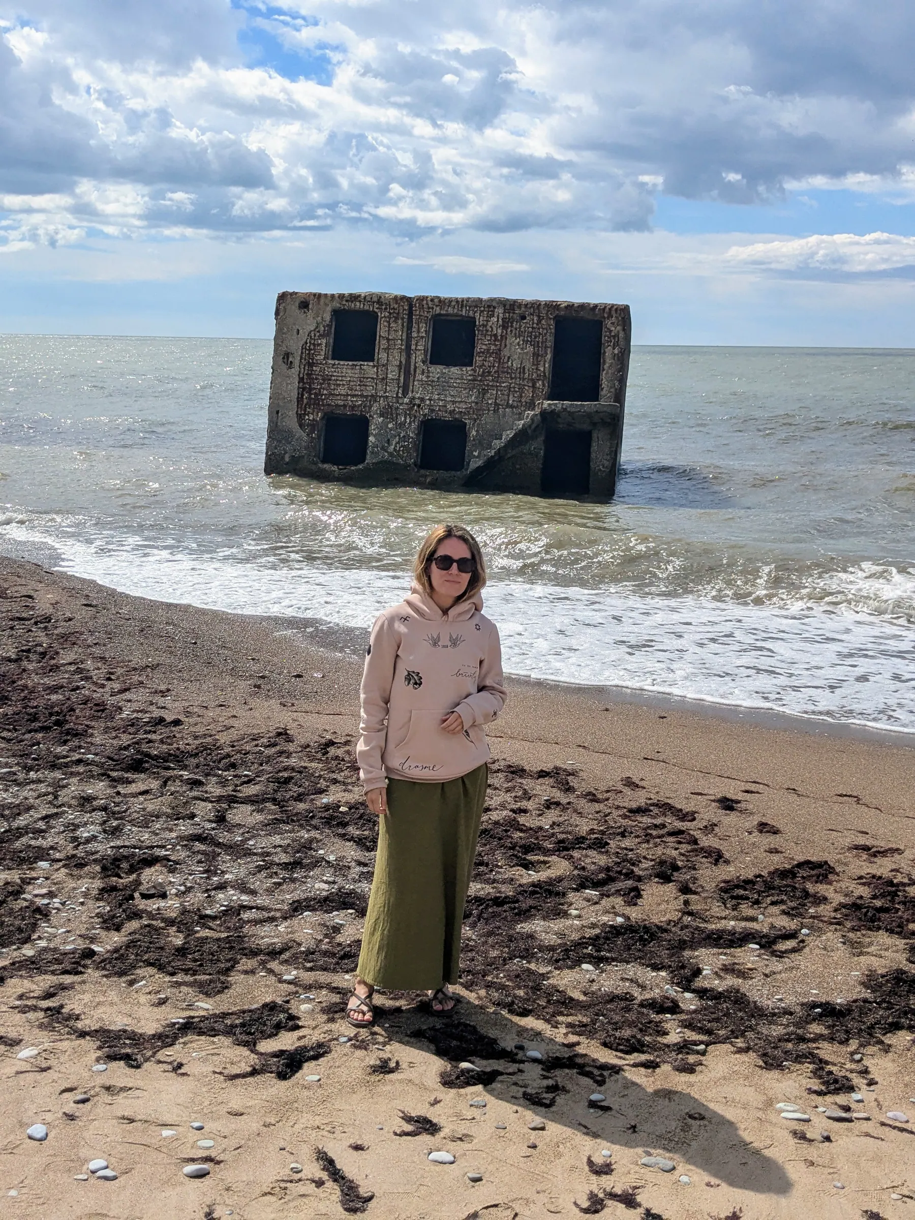 A traveler on the beach with Artillery Battery No. 3 half-submerged in the sea