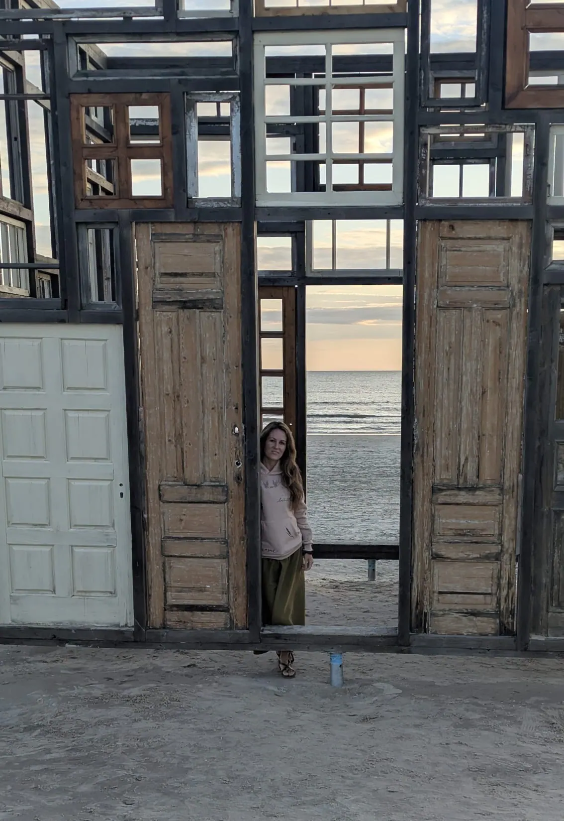 A traveler standing within the wooden door installation on Liepāja beach