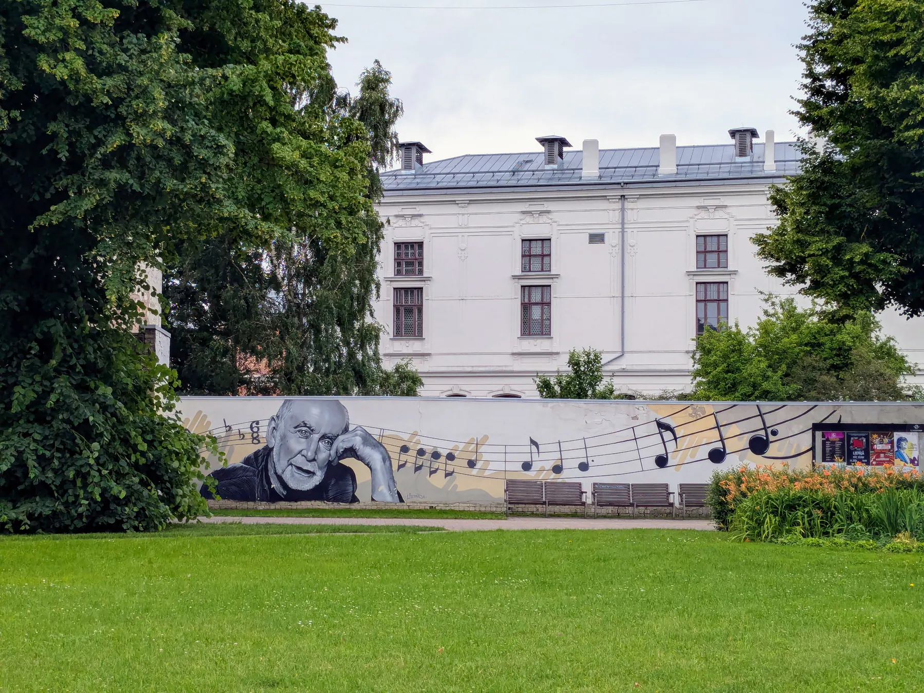 A black-and-white mural with musical notes beside a Liepāja garden