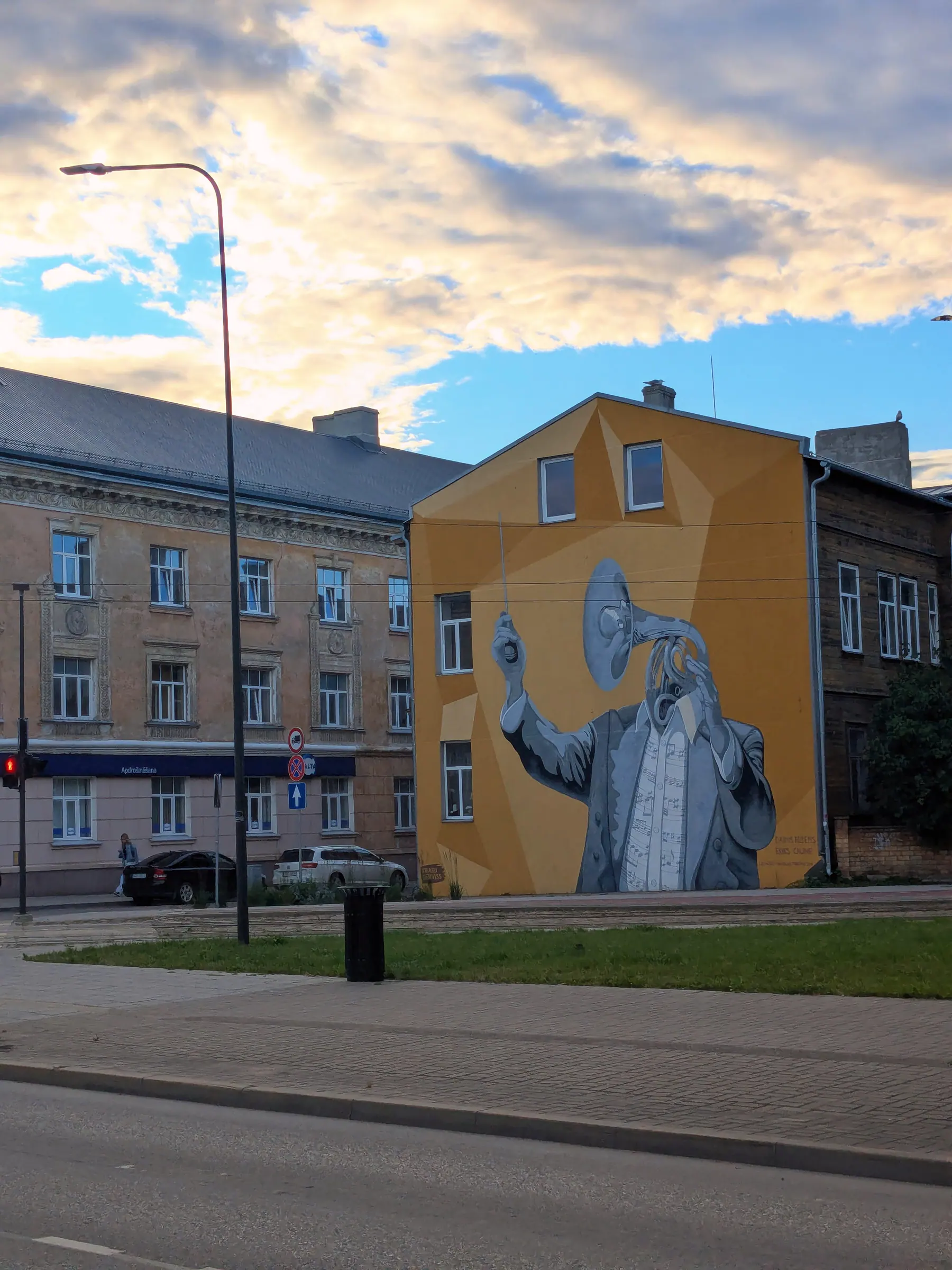 A woman painted across the yellow side wall of a Liepāja building