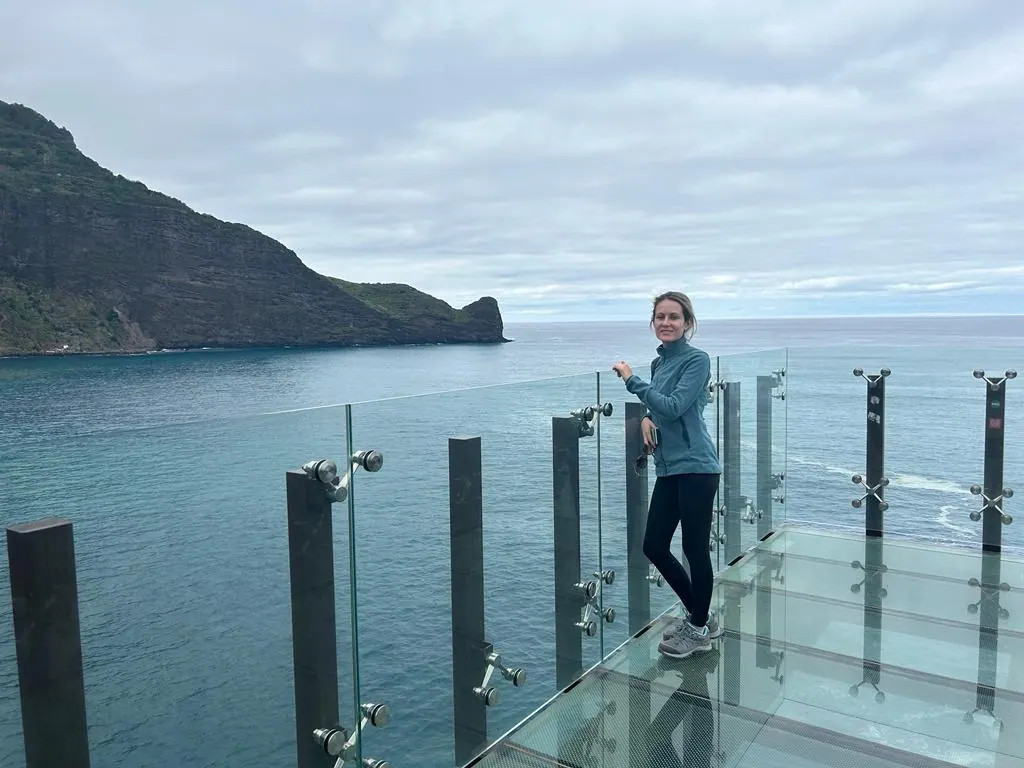 A traveler standing on the glass viewpoint at Miradouro do Guindaste