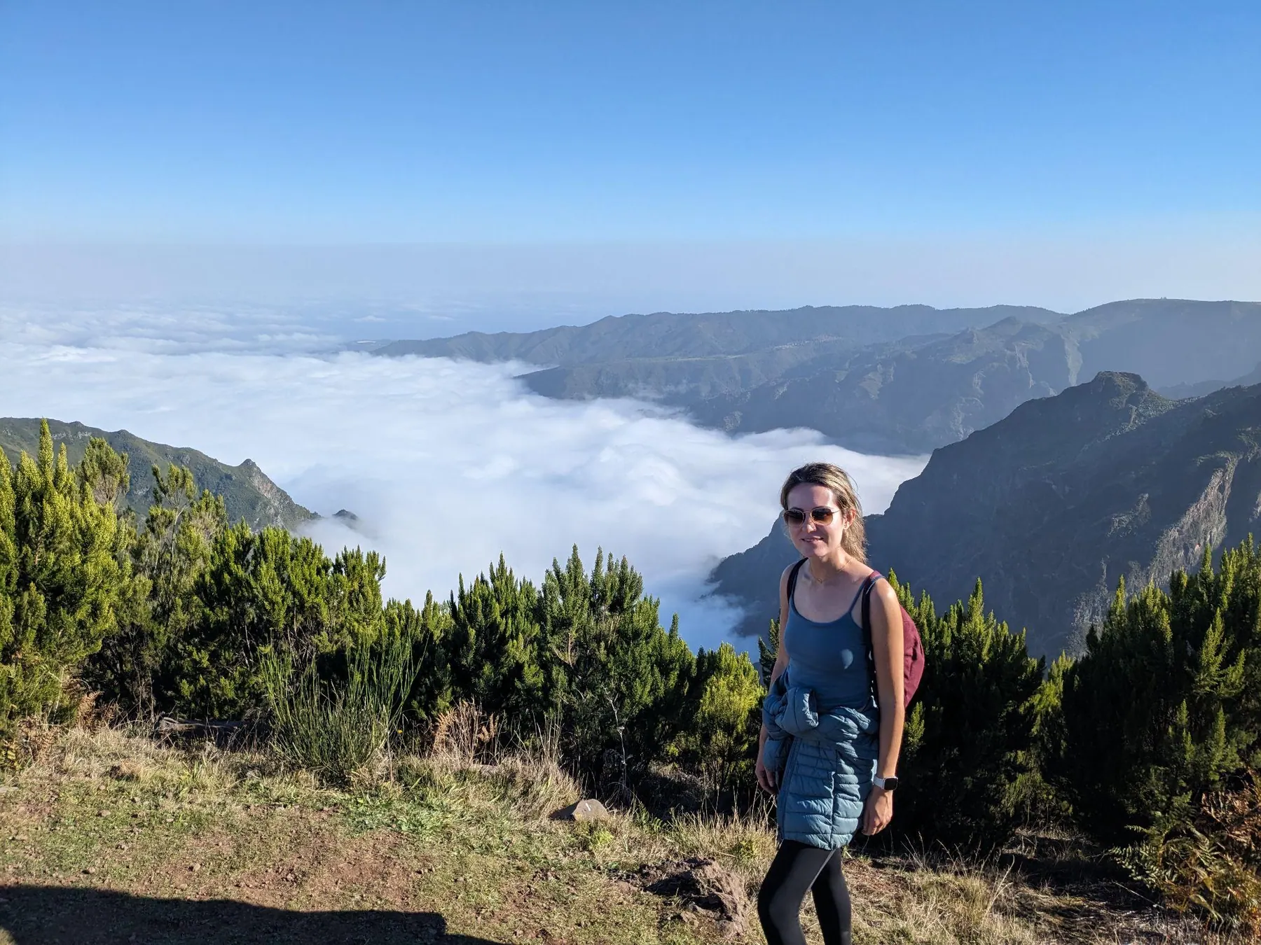 A traveler standing above clouds on a Madeira mountain trail