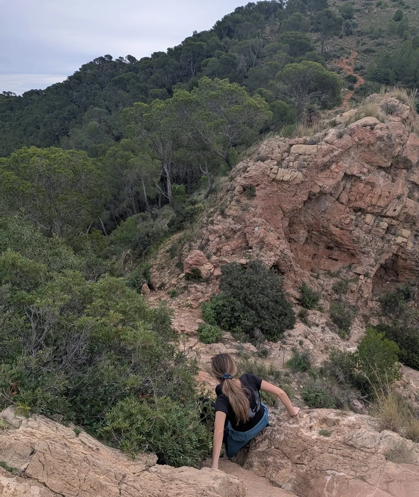 A hiker climbing the rocky final slope toward La Creueta above Náquera