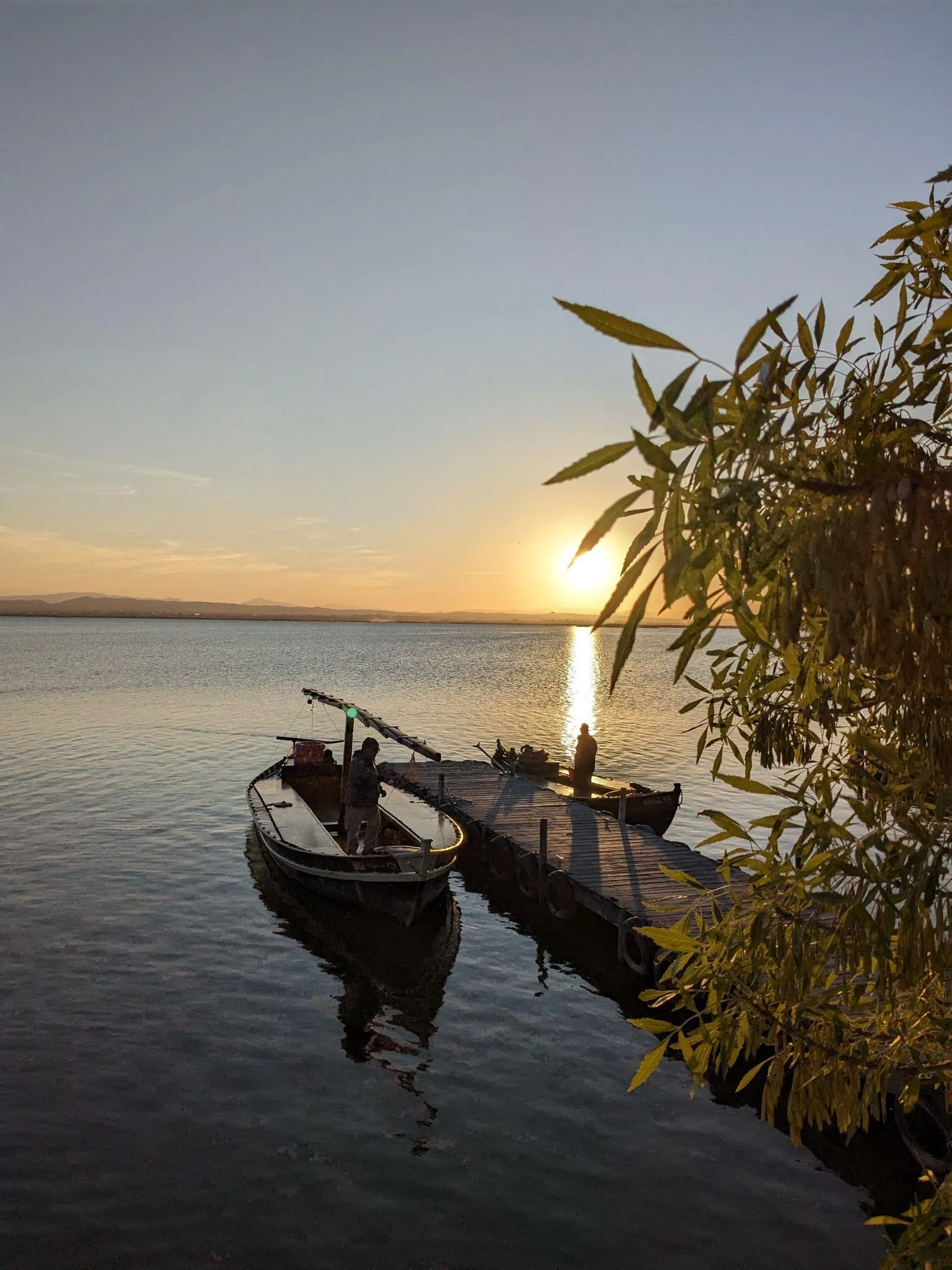Traditional wooden boat moored at a pier by Mirador del Pujol in the Gola de Pujol at sunset
