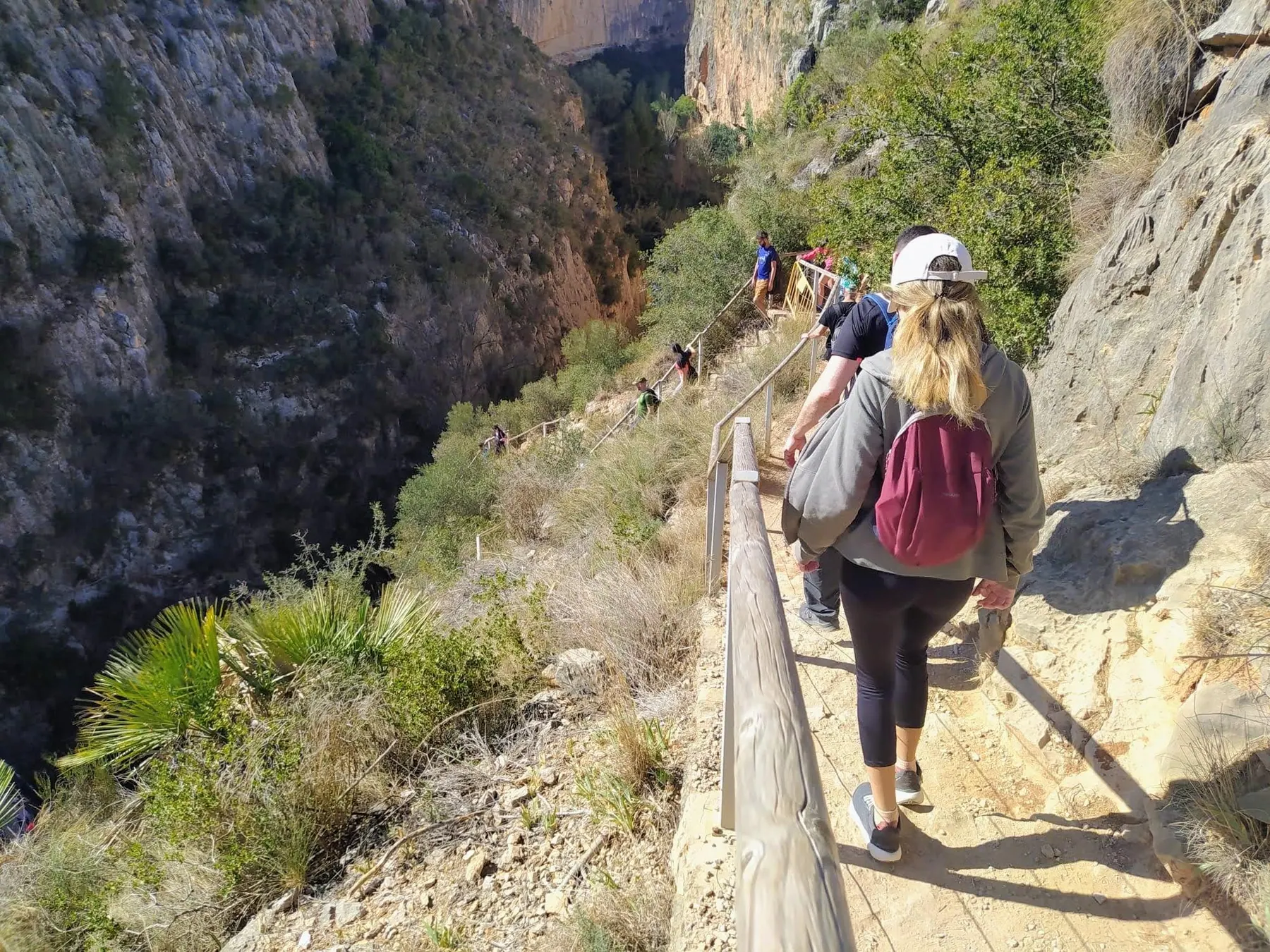 Hikers descending a wooden stairway into the deep rocky canyon towards the riverbed