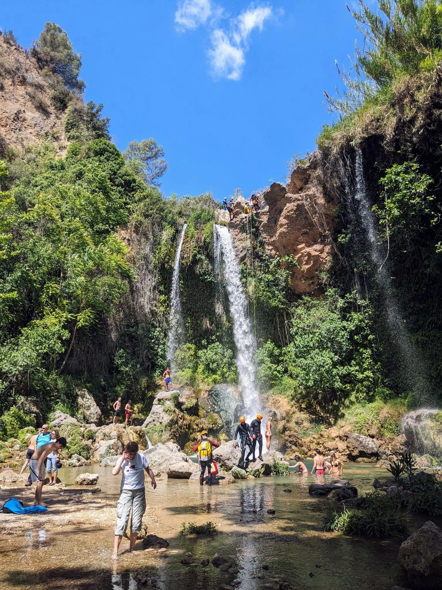 Two streams of Cascada del Salto falling over rocks with visitors below on Anna's Three Waterfalls route