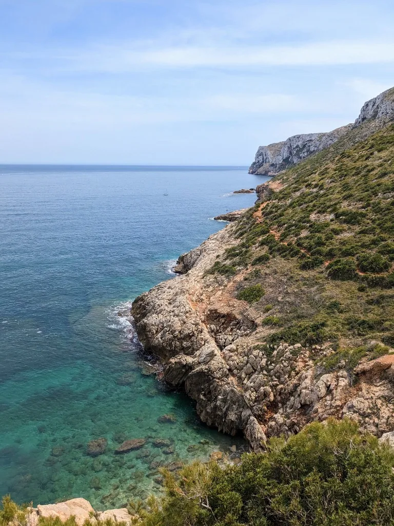 Rocky coastal trail along cliffs and turquoise Mediterranean waters leading to Cova Tallada
