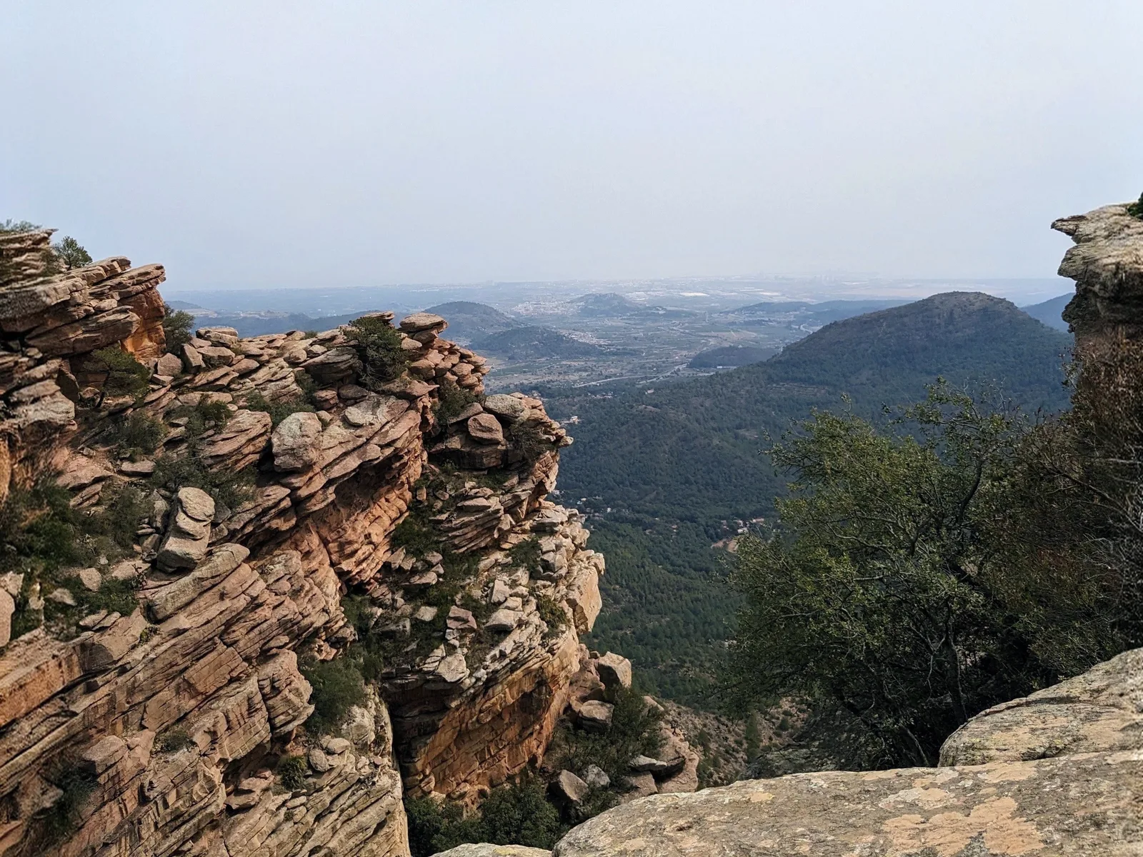 Rugged red sandstone rocks overlooking the pine-covered valleys from Mirador del Garbí