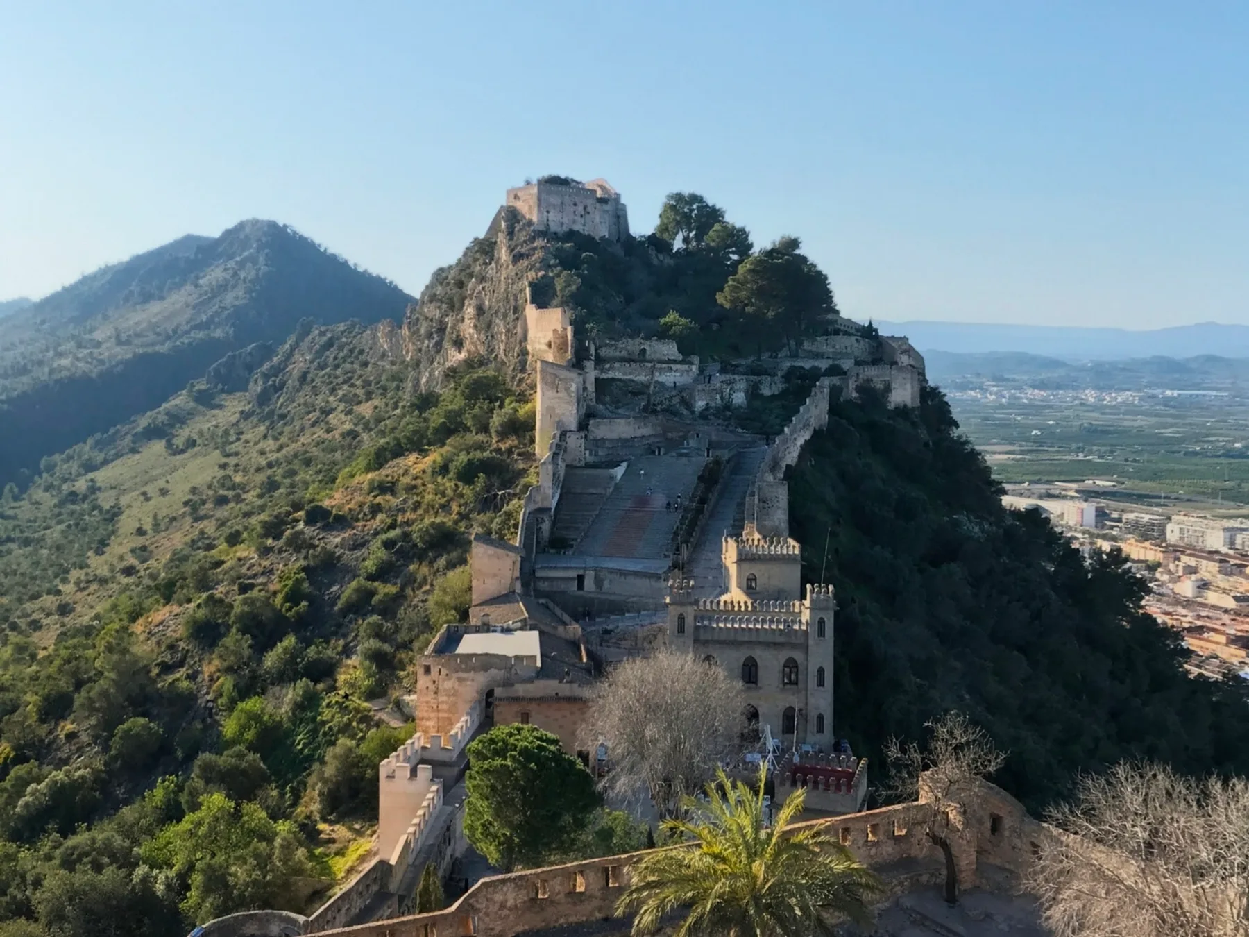 The stone fortress of Castell de Xàtiva stretching across a steep mountain ridge above the Valencian countryside