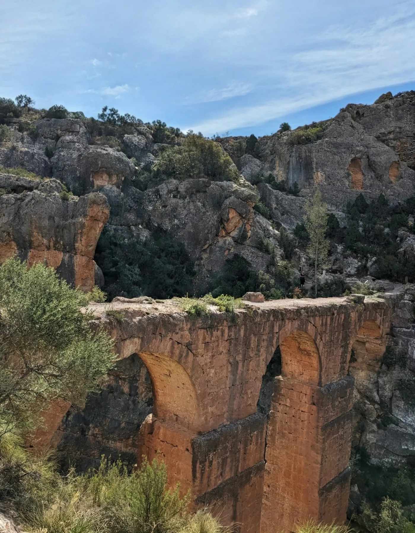 The towering stone arches of the Roman aqueduct of Peña Cortada bridging a deep limestone gorge near Chelva