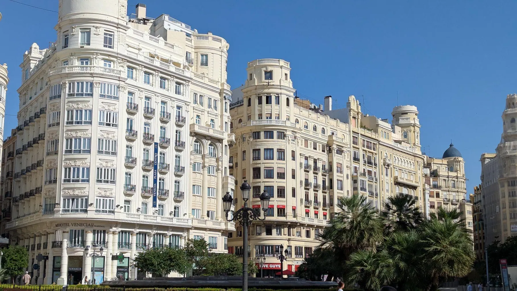 Historic architectural facades and palm trees across Plaza del Ayuntamiento in daytime