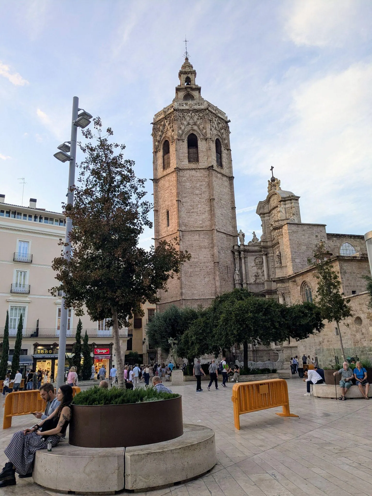 Pedestrian promenade and palm trees on Plaza de la Reina with Cathedral bell tower in background