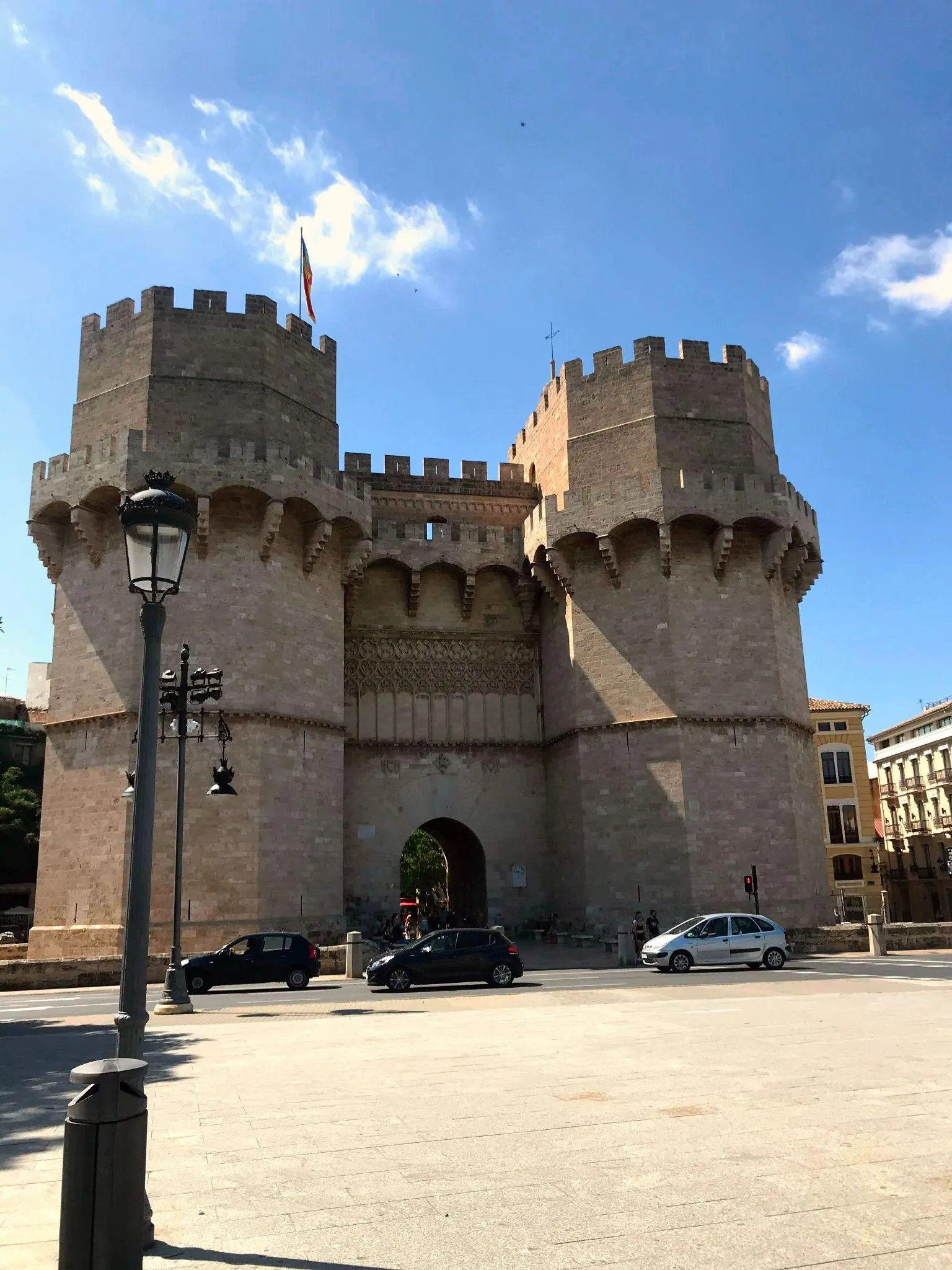 Crenellated Gothic stone defensive towers and gate of Torres de Serranos under blue sky