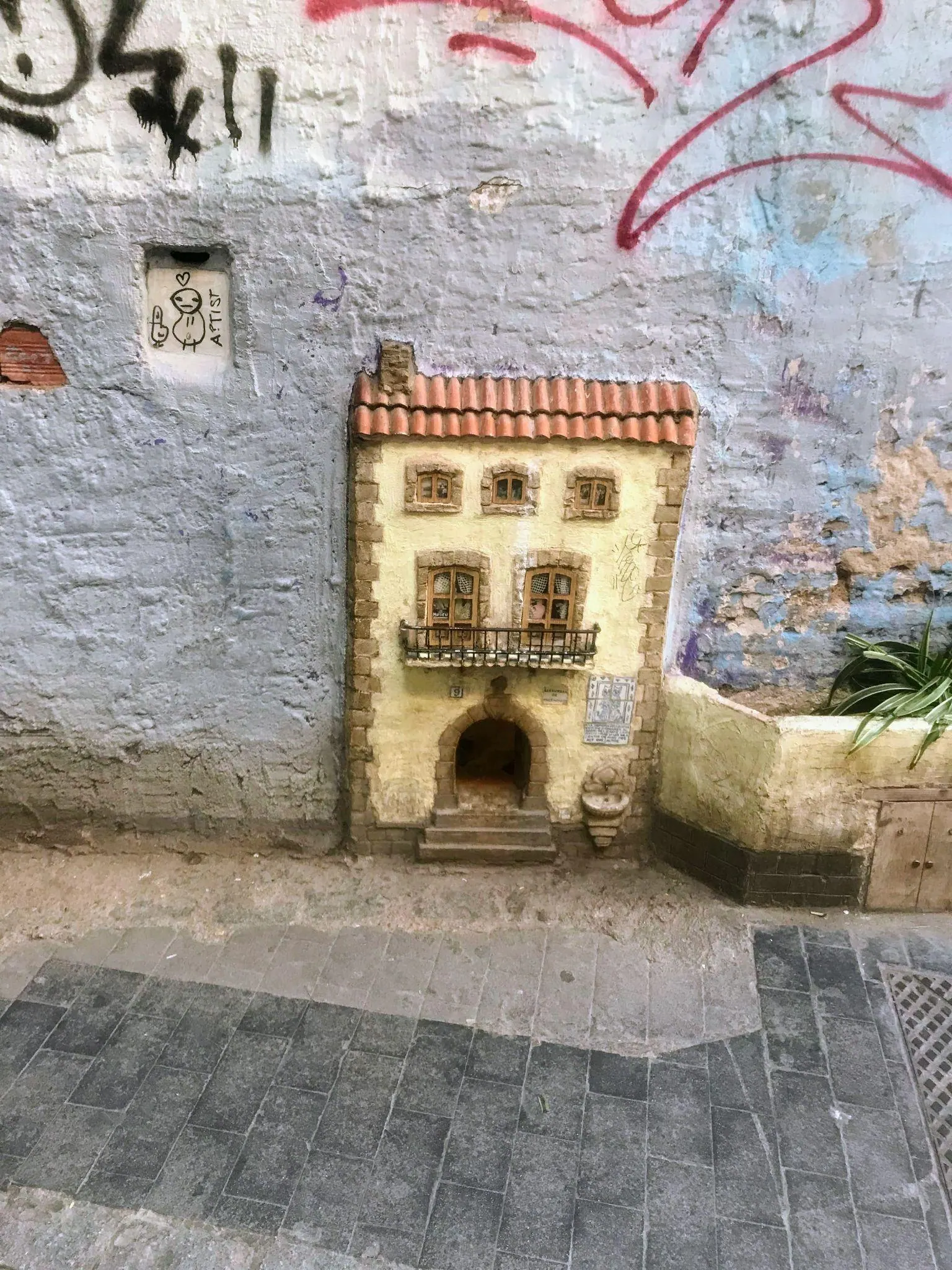 Detailed miniature stone facade and cat door of Casa dels Gats on Calle del Museo