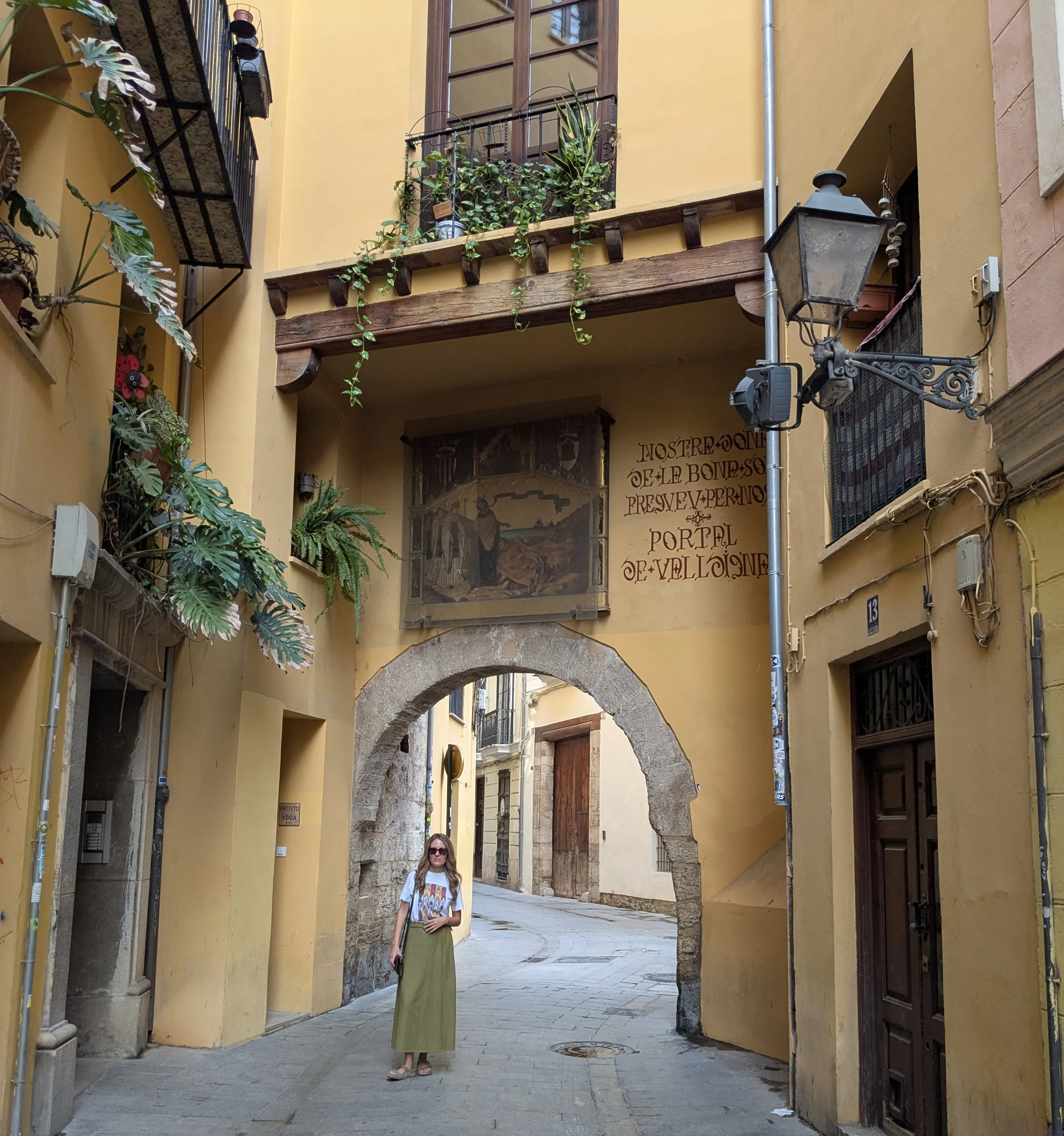 Historic stone archway of Portal de Valldigna with medieval inscription and traveler standing underneath
