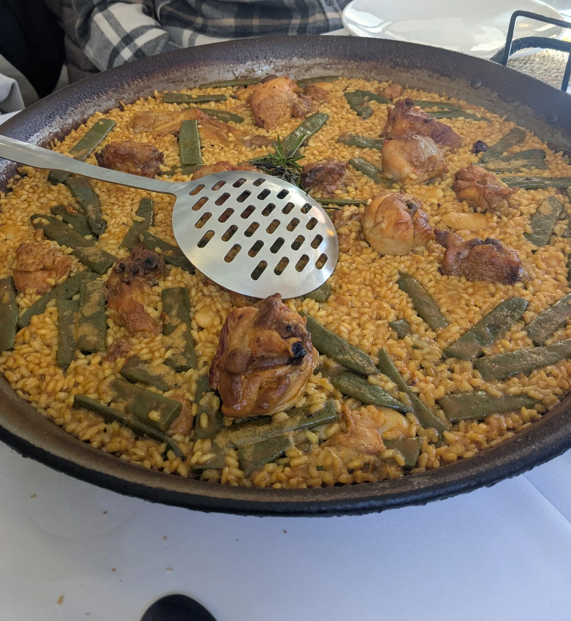 Authentic Valencian paella in a traditional wide pan with chicken, rosemary, green beans, and large garrofó lima beans