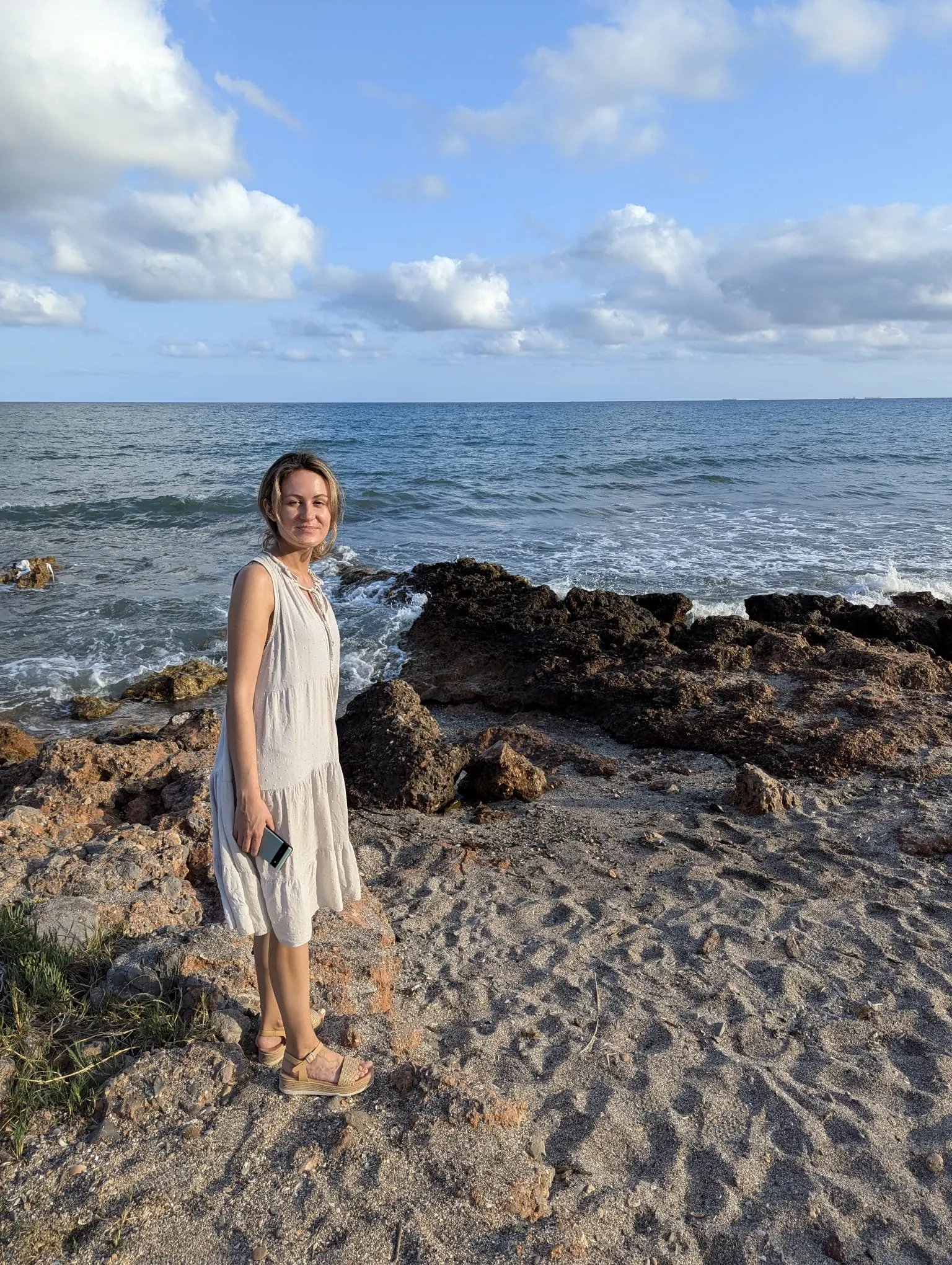 A traveler standing on the rocky shore beside the Mediterranean near the Vía Verde del Mar